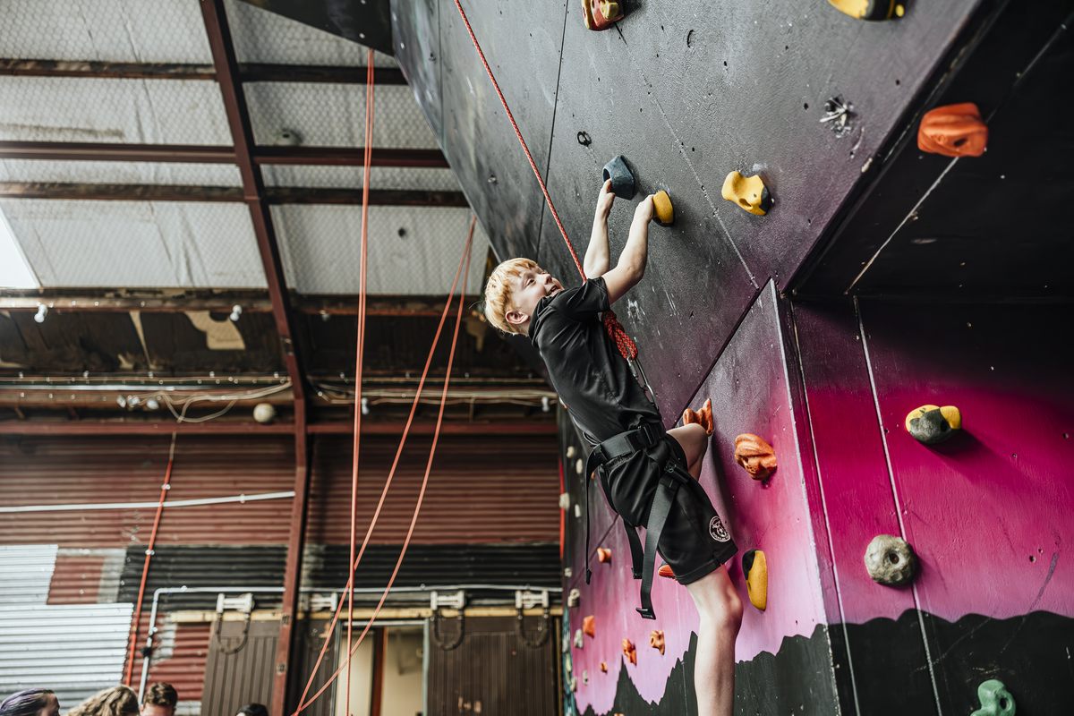 A young climber reaching for a hold on the Climbing Wairarapa mural wall