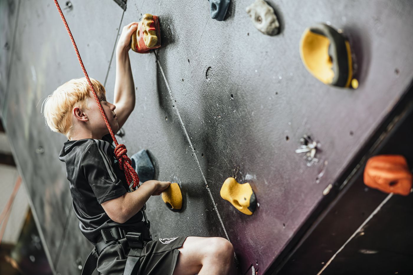 A young climber reaching for a hold on the wall